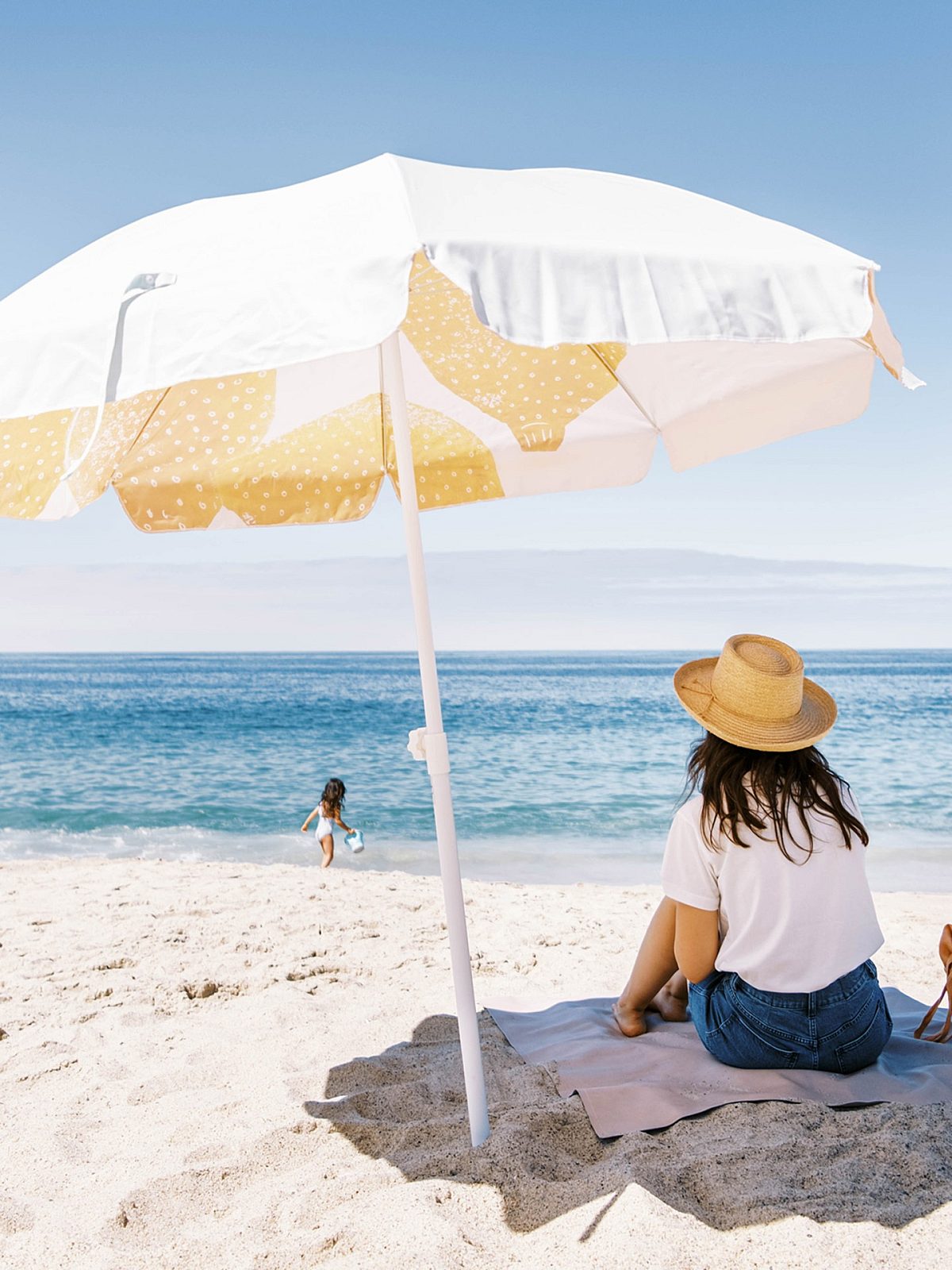 mother wearing a straw hat and kid playing in the beach