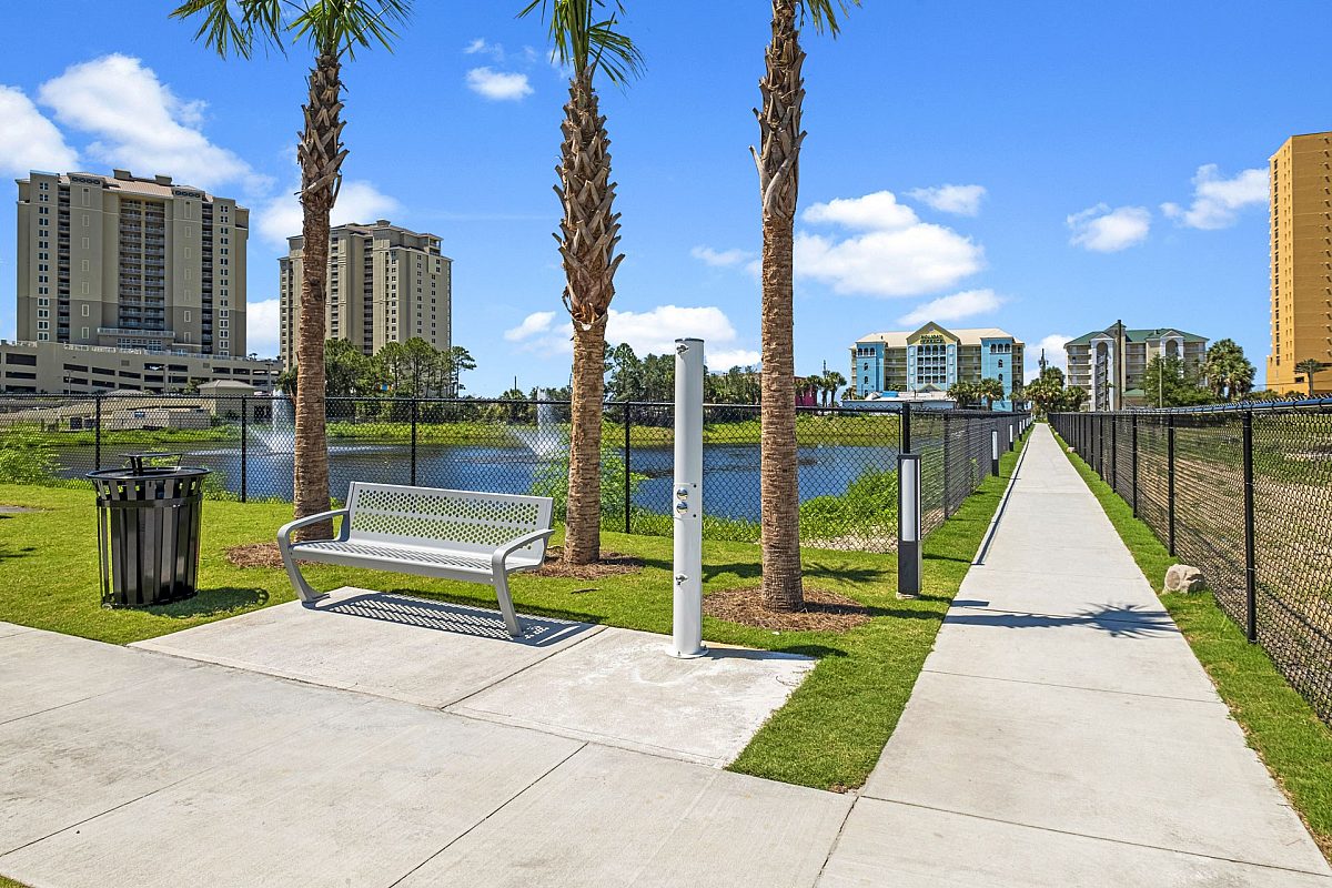 apartment sidewalk with bench, palm tree, and bin