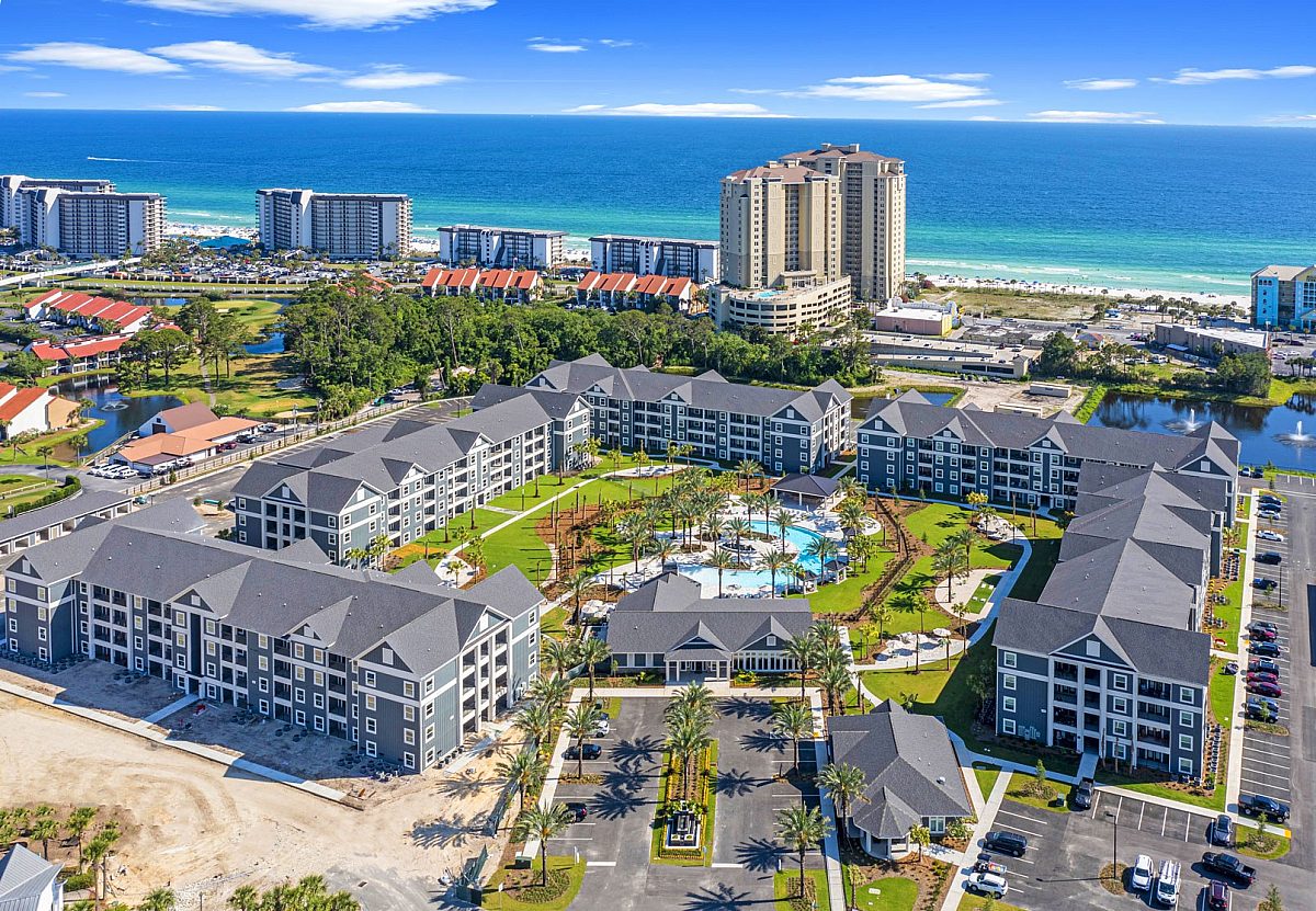 top view of an apartment complex with swimming pool, parking space, and palm trees